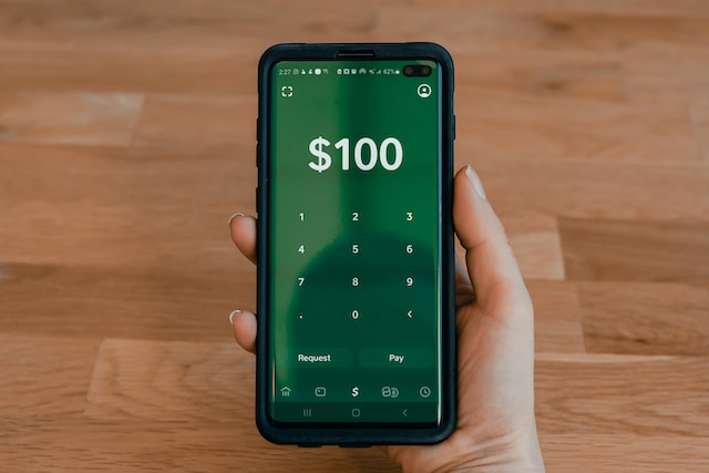 La pantalla del teléfono muestra 100 dólares en números. 