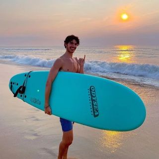 un uomo che tiene in mano una tavola da surf su una spiaggia