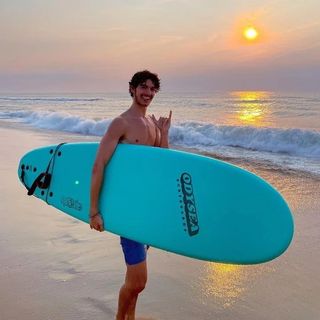 ein Mann hält ein Surfbrett am Strand