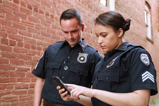 警察官と婦人警官が携帯電話を見ている写真。