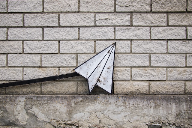 A paper airplane against a brick wall signifying how to repost on Instagram.