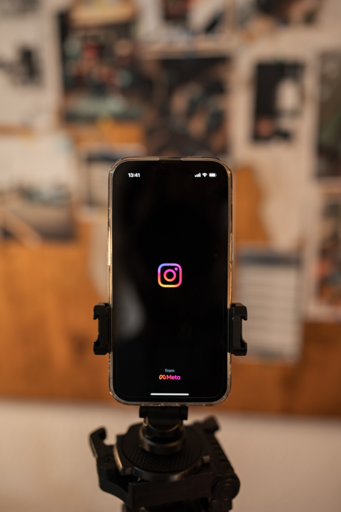 Iphone dans un support avec le logo Instagram sur fond noir.