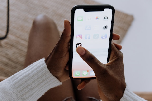 pexels-cottonbro-studio-5081920 | Path Social شخص يحمل جهاز iPhone يفتح تطبيق TikTok.
