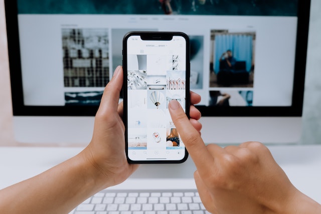 pexels-cottonbro-studio-5082579 | Path Social Person holding a smartphone in front of a desktop computer
