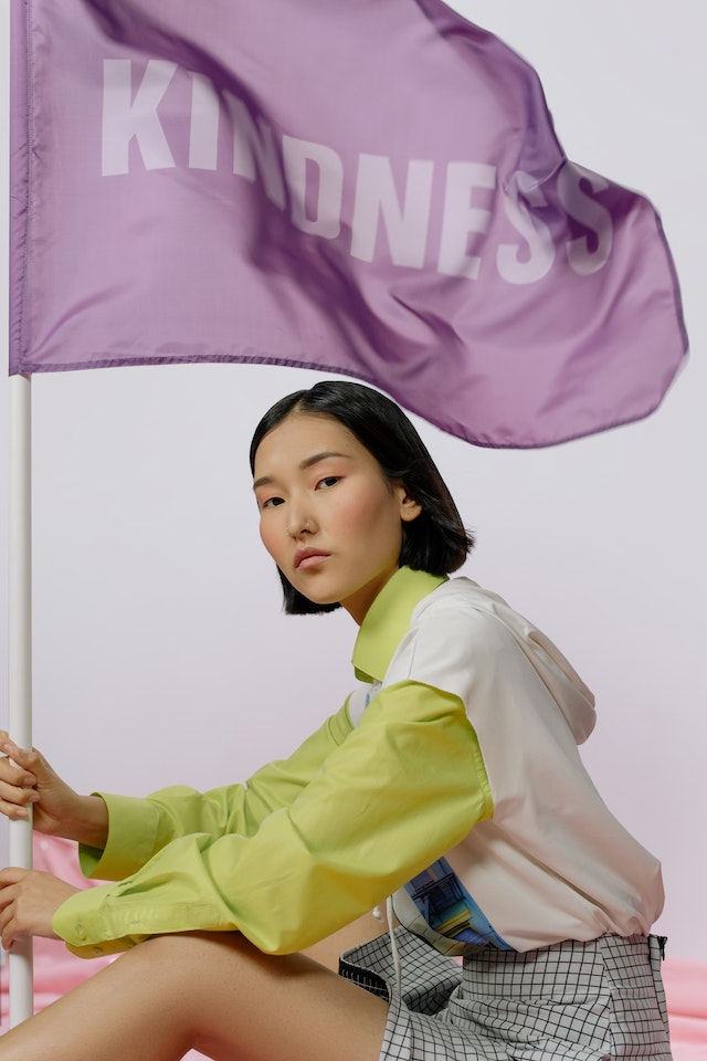 Femme avec un drapeau violet portant le mot &quot;Kindness&quot; (bonté)