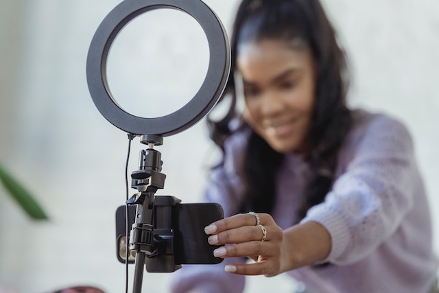Path Social young woman setting up ring light and smartphone to create content
