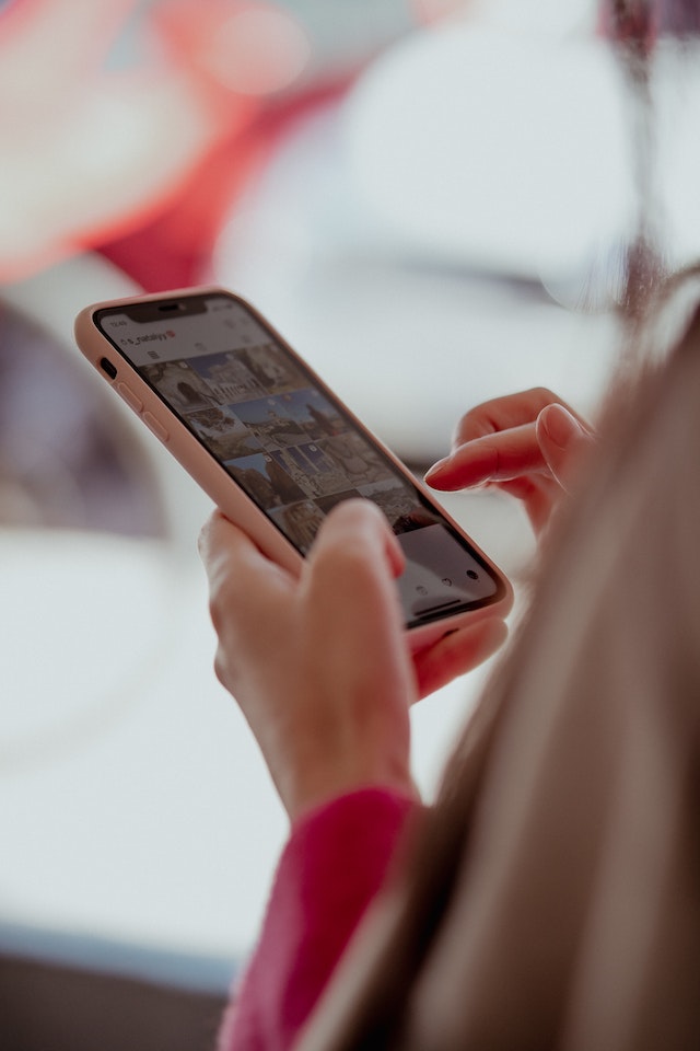 Woman holding a smartphone, using Instagram.