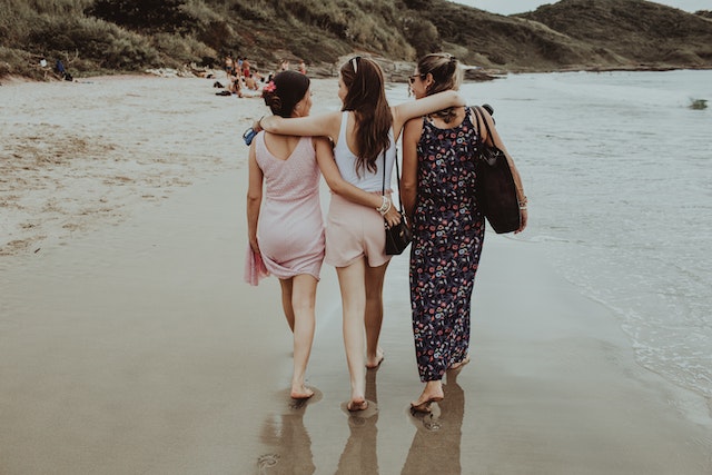 Tre donne che camminano sulla spiaggia.
