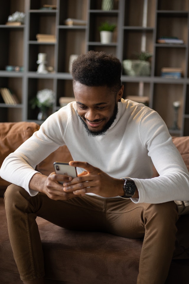 Un homme regarde son téléphone en souriant.