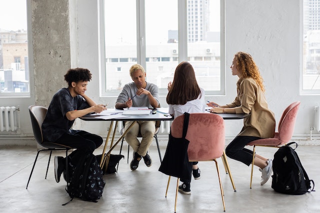 Four people sitting at a desk in a meeting.