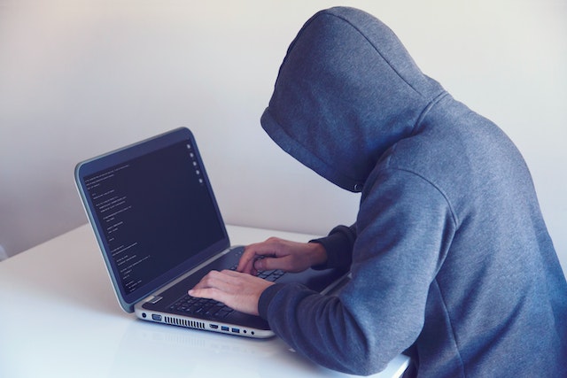 Eine Person im Kapuzenpulli hackt sich in einen Laptop.