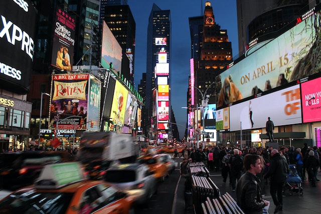 O stradă din New York City, noaptea, plină de panouri publicitare.