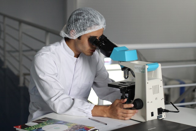 Man looks at a specimen through a microscope.