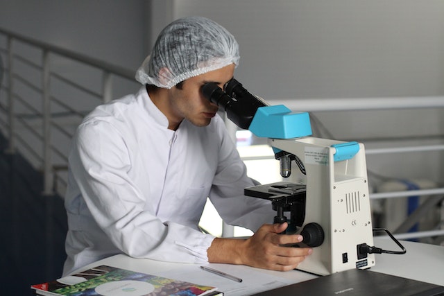 Un hombre observa un espécimen a través de un microscopio.