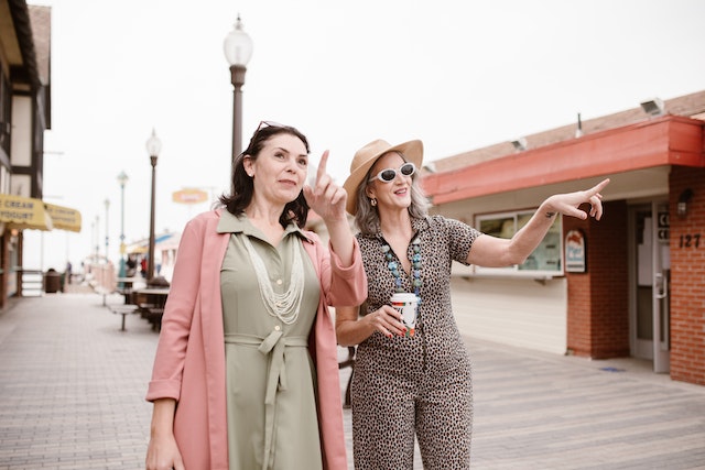 Two middle-aged women standing and pointing.