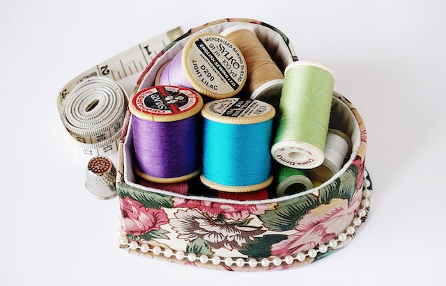 Basket of assorted thread, a tape measure, and a thimble.