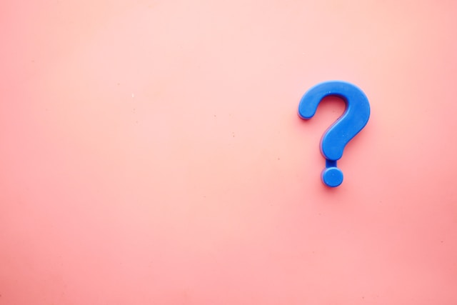 A blue question mark on pink background.