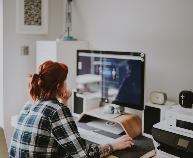 Mulher ao computador a pensar como mudar o seu nome de utilizador do Instagram.