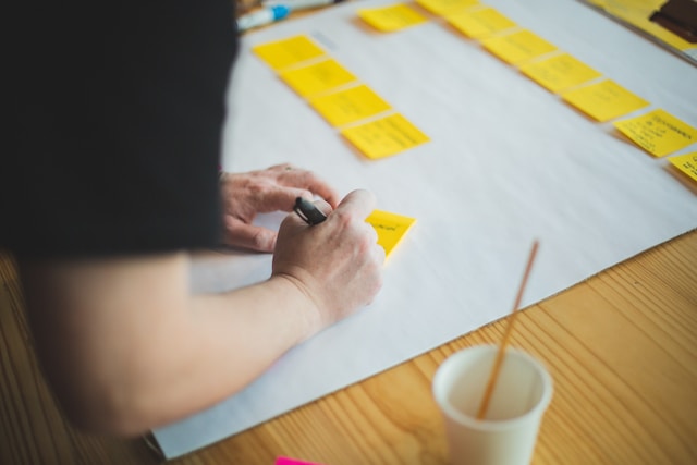 Qualcuno che scrive su dei post-it per creare un programma di pubblicazione per Instagram.