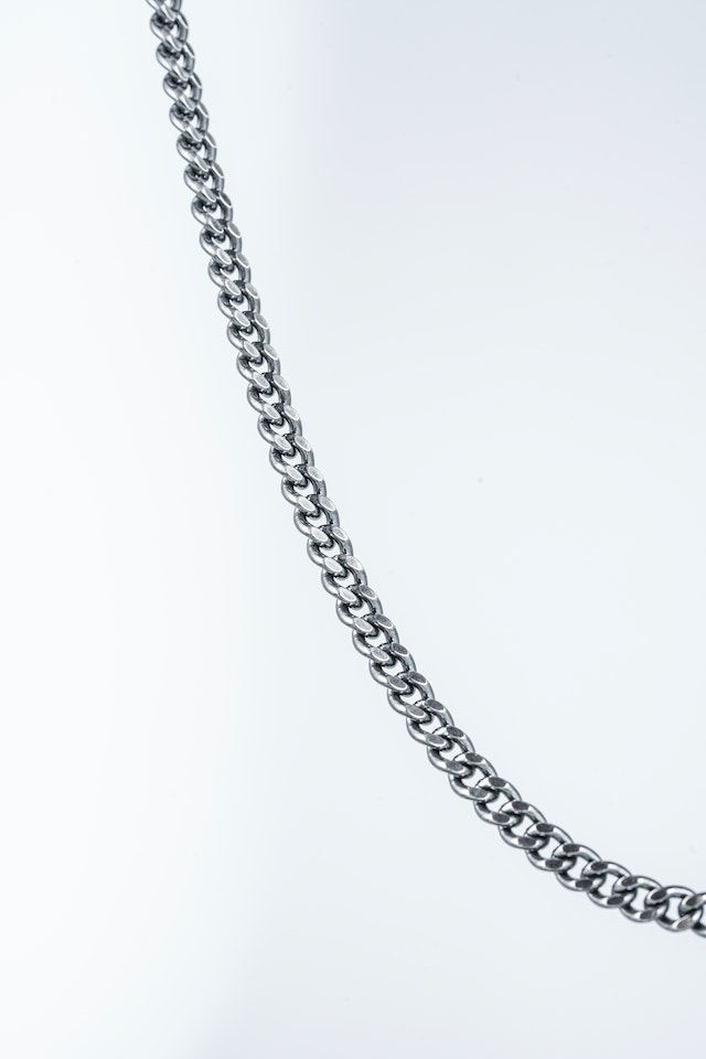 Silver Cuban link chain against white background.
