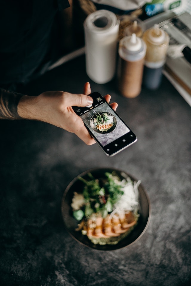 Pessoa a tirar uma fotografia de comida numa tigela