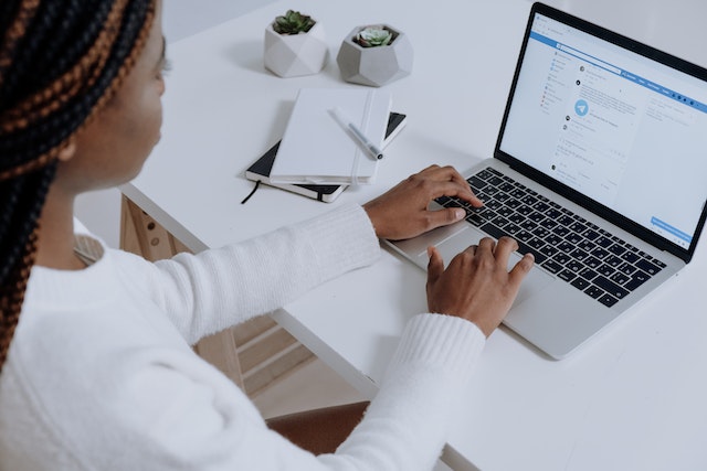 Person in White Long Sleeve Shirt Using Facebook on Macbook Air