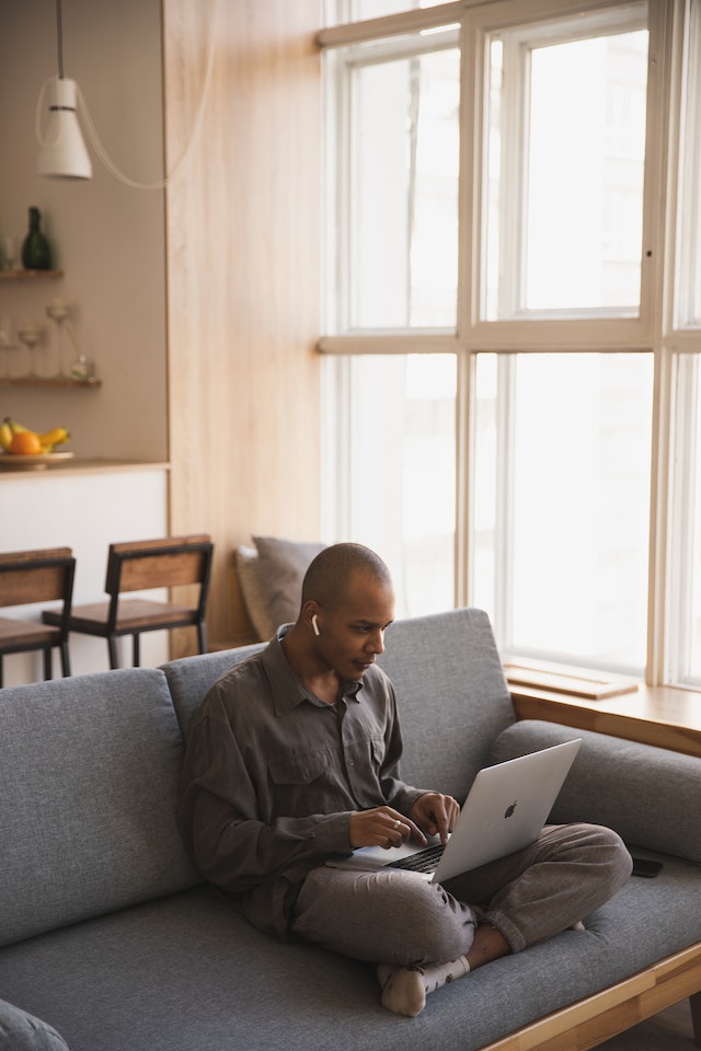 Homme sur le canapé utilisant son ordinateur portable.