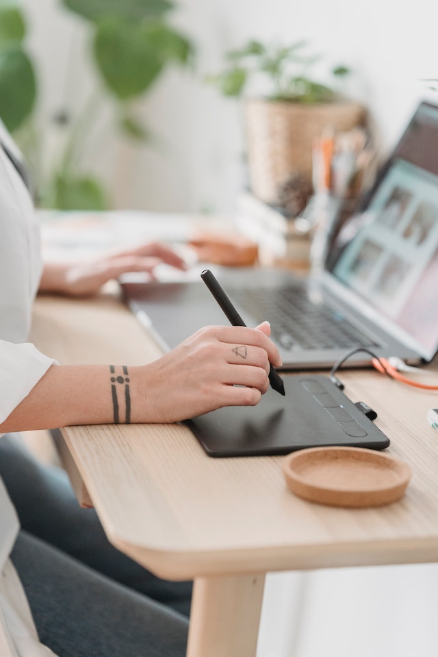 Gezichtsloze vrouw werkt op laptop en grafisch tablet