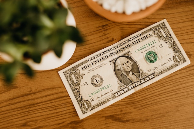 Uma nota de um dólar sobre uma mesa de madeira.