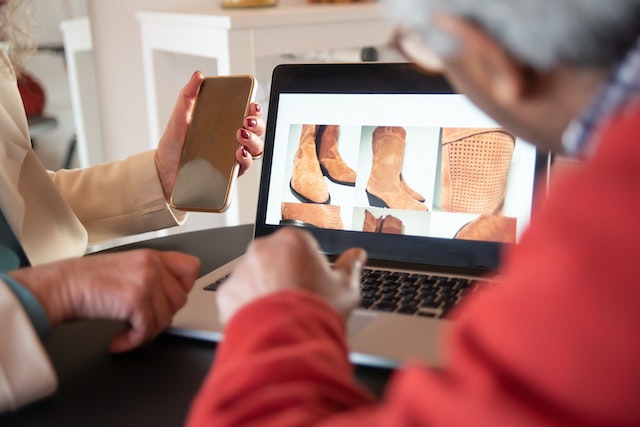 Two people shopping online through a phone and laptop.