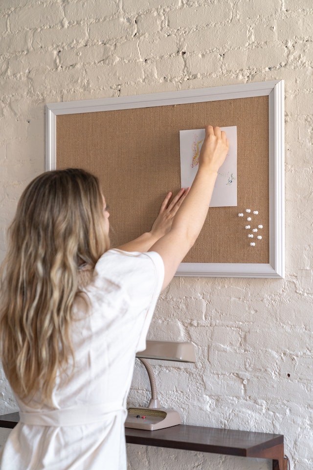 Woman mounting sketch on display board.
