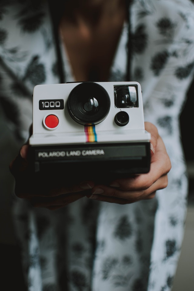 Personne tenant un appareil photo terrestre Polaroid blanc