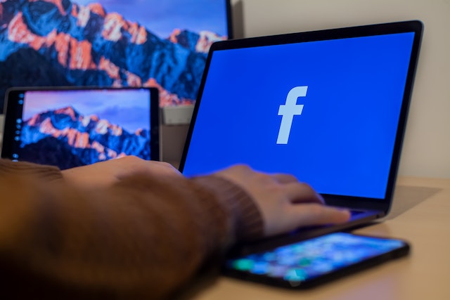 Facebookロゴの入ったノートPCを使用する人