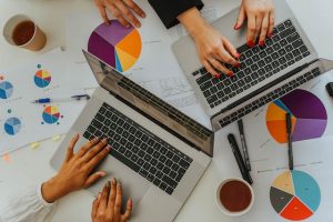 Persons Using Laptops on Table with Charts