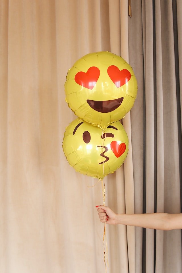 Balloons with emoji faces printed on them.