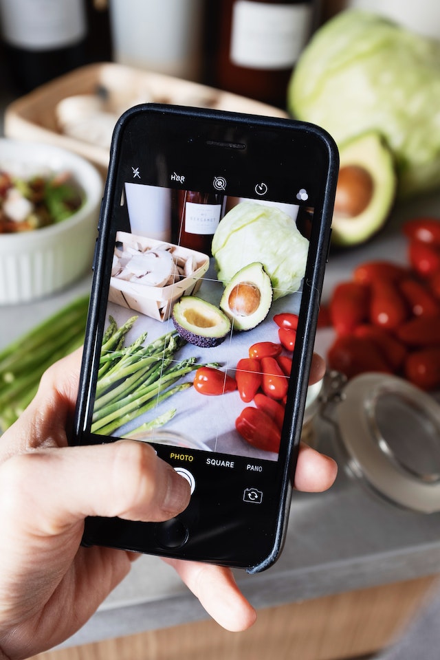 Una persona che fotografa il cibo con il telefono.