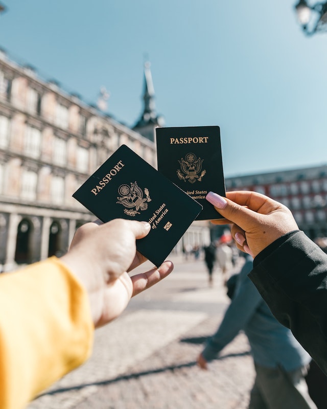 Two hands, each holding a passport.