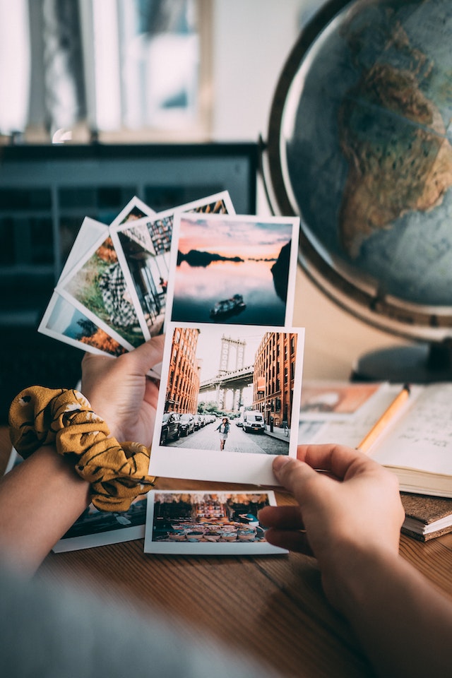 Person hält weißes Druckerpapier mit Fotos