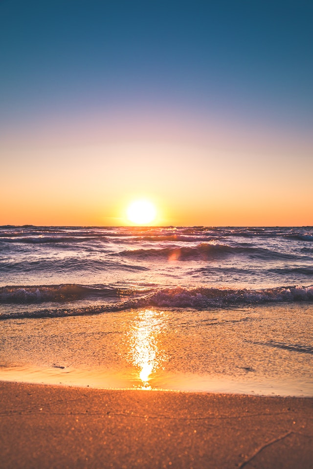 Il sole tramonta all'orizzonte della spiaggia.