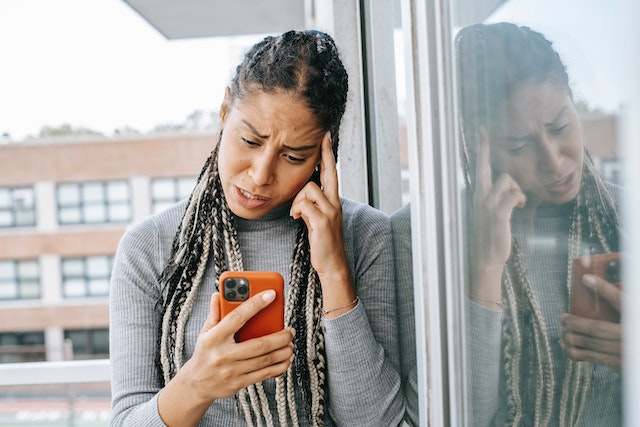 Gefrustreerde vrouw kijkt naar telefoon.