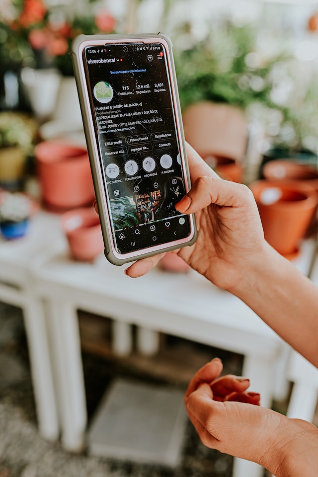 Unsichtbare Person, die ein Android-Smartphone in der Hand hält, während sie die Seite Instagram eines Unternehmens anschaut.