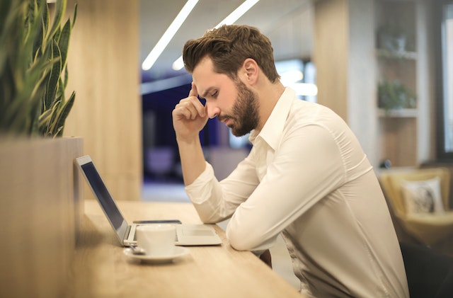 Man met hand op slaap kijkt naar laptop vanwege Instagram link in bio werkt niet.