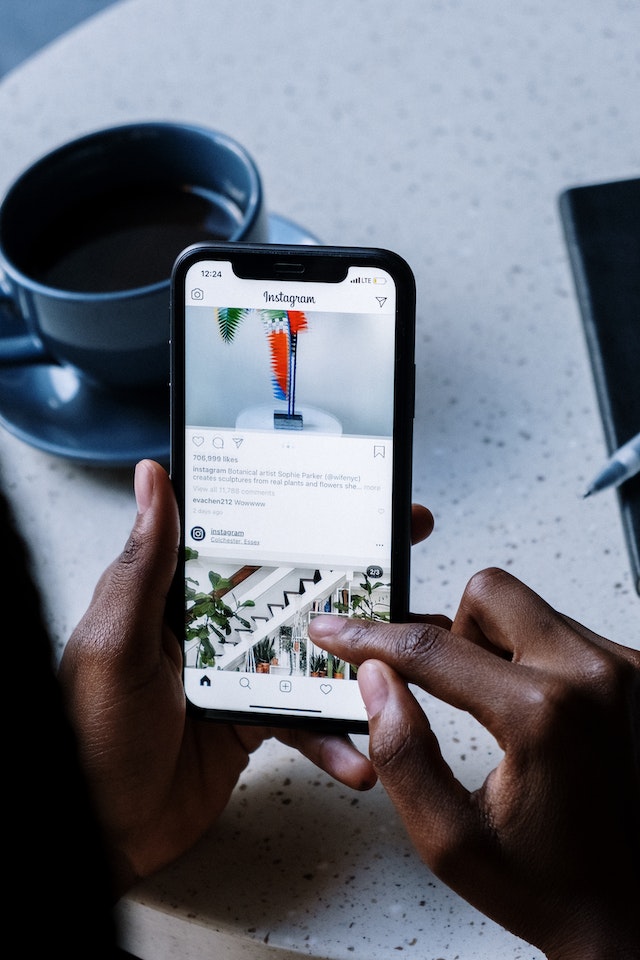 pexels-cottonbro-studio-5053834 | Path Social Unseen person holding a black iPhone while scrolling on Instagram.
