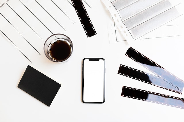 Smartphone and filmstrips arranged on table with coffee and notebook