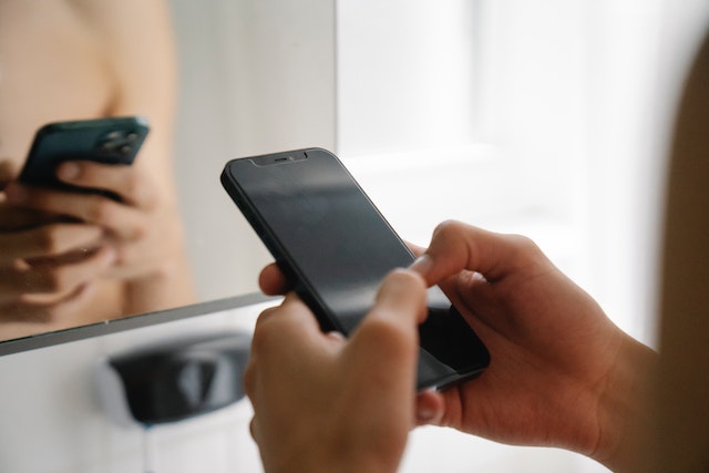 Unseen person using an all-black smartphone.