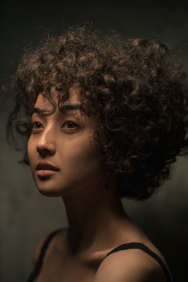 Künstlerisches Foto einer jungen, attraktiven Frau mit lockigem Haar.