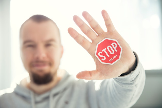 Homem com um sinal de stop na palma da mão.