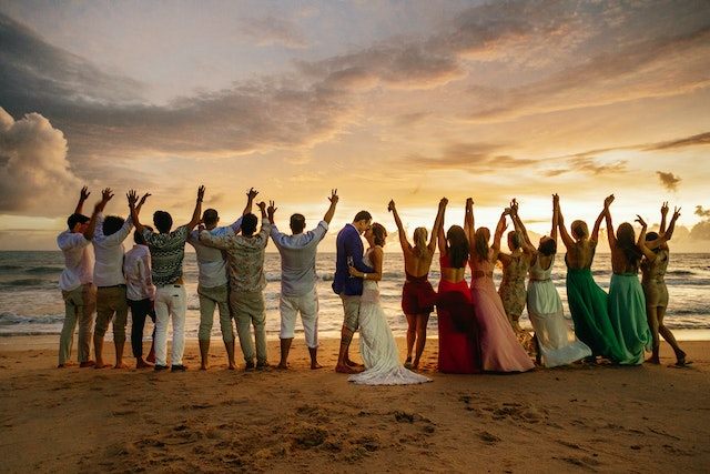 أشخاص يحتفلون بمناسبة زفاف على الشاطئ.