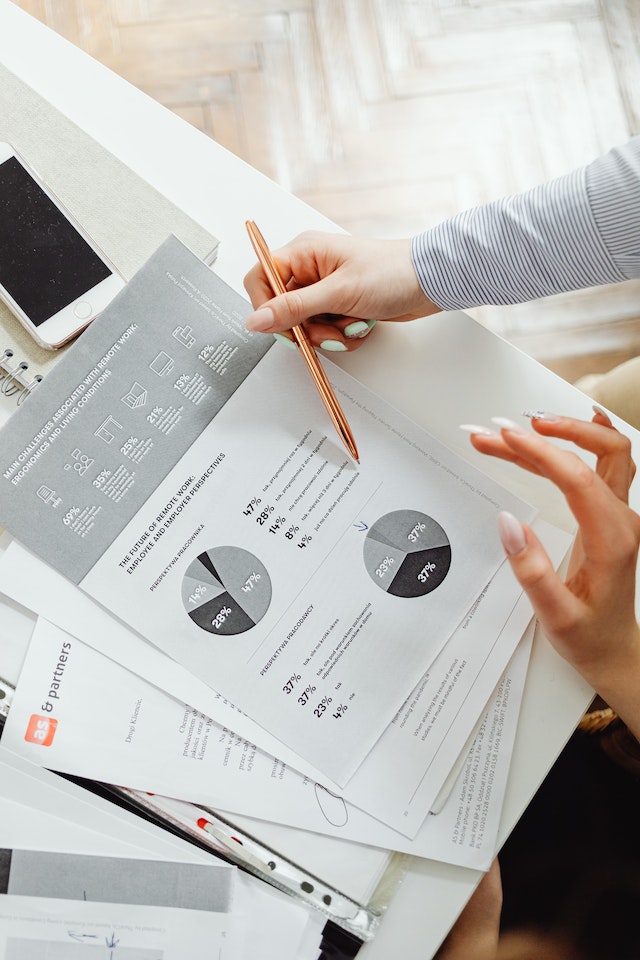 Close-up photo of unseen people reviewing accounting documents while holding a pencil.