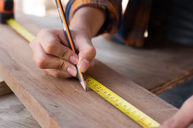 Mujer midiendo con lápiz amarillo sobre tabla